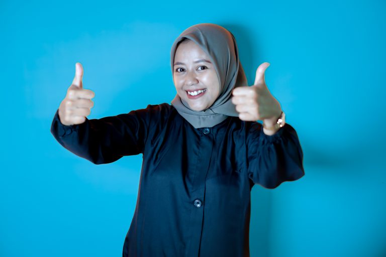 Asian woman wearing a hijab posing in an agreeable OK gesture with 2 thumbs up